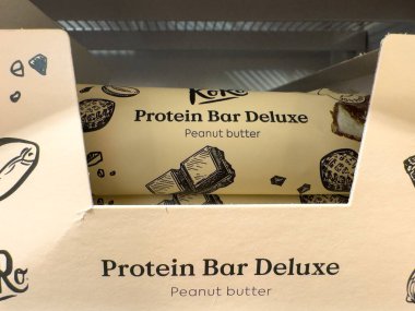 Villach, Austria - October 09, 2025: Protein Bar Deluxe packaging showcases peanut butter flavor with artistic illustrations and vibrant colors, enhancing visual appeal