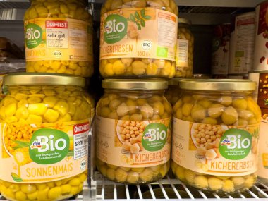 Villach, Austria - October 09, 2025: Organic chickpeas and corn jars are neatly arranged on supermarket shelf, highlighting sustainable food choices and vibrant packaging