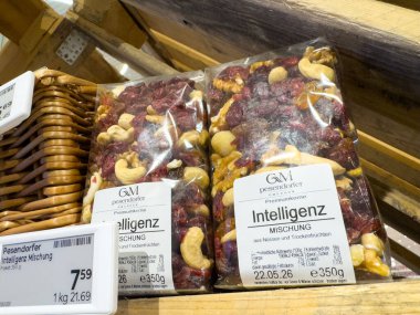 Villach, Austria - October 09, 2025: Premium bags of mixed nuts and dried fruits are arranged on wooden shelves in a grocery store, highlighting healthy snack choices