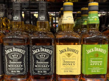 Villach, Austria - October 09, 2025: Jack Daniel's whiskey bottles are arranged on a shelf, featuring honey and apple flavors, emphasizing the brand's rich Tennessee tradition