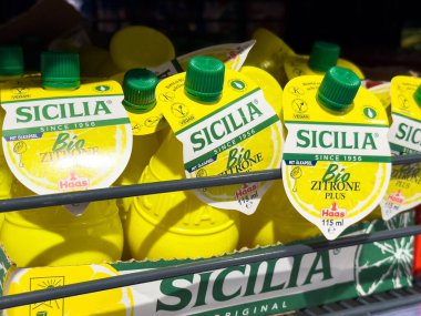 Villach, Austria - October 09, 2025: Sicilia lemon juice bottles arranged on a shelf, featuring bright yellow caps and labels, perfect for cooking and drinks