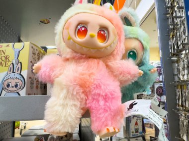 Villach, Austria - October 09, 2025: Colorful plush toy with big eyes and soft fur is showcased on a shelf filled with other adorable collectibles