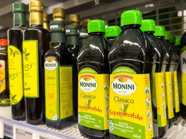 Villach, Austria - October 09, 2025: Monini Classico olive oil bottles arranged on supermarket shelf, featuring bright labels and different sizes for cooking and dressing