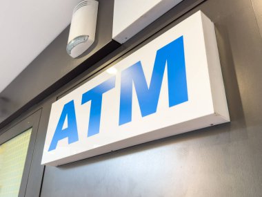 Trieste, İtalya - 14 Ekim 2025: Çağdaş bankacılık teknolojisini ve kullanıcılar için kolaylığı temsil eden gösterişli bir duvarda mavi harflerle aydınlatılmış ATM tabelası