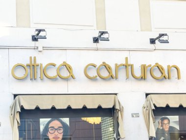 Trieste, İtalya - 14 Ekim 2025: Ottica Carturan mağaza vitrininde çağdaş tasarım estetiğine sahip canlı kentsel bir çevrede şık gözlük sergileniyor
