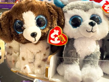 Trieste, İtalya - 14 Ekim 2025: İki Ty Beanie Boo pelüş oyuncağı, bir kahverengi köpek yavrusu ve gri kabuklu, büyük gözlü ve yumuşak kürklü, renkli bir ortamda sergilenen