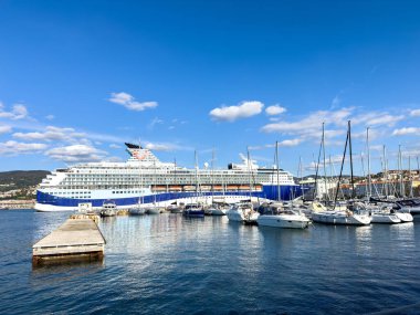 Trieste, İtalya - 14 Ekim 2025: Büyük yolcu gemisi, sakin sularla dolu mavi bir gökyüzünün altında, yelkenlilerle çevrili olarak limanda demirledi.