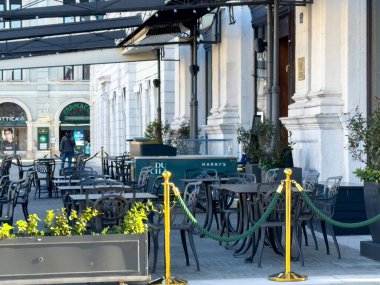 Trieste, İtalya - 14 Ekim 2025: Açık kafe sahneleri boş masa ve sandalyeler, yemyeşil bitkiler ve canlı bir şehir atmosferinde güzel mimari ile çevrili