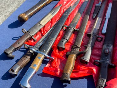 Villach, Avusturya - 11 Ekim 2025: Kırmızı kumaş üzerine dizilmiş klasik askeri süngüler, benzersiz tarihi silah tasarımları ve zanaatkarlığı sergiliyor