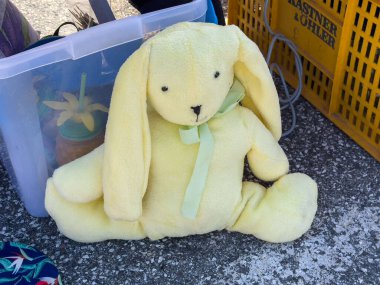 Villach, Avusturya - 11 Ekim 2025: Sarkık kulaklı, yeşil kurdeleli, plastik bir kap ve sepetin yanına yerleştirilmiş sarı doldurulmuş tavşan