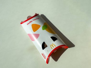 Villach, Avusturya - 11 Ekim 2025: Canlı geometrik tasarımlı McDonald 's sıcak aperatif ambalajı, hafif bir yüzeyde dinleniyor, marka kimliği ve yiyecek cazibesini vurguluyor