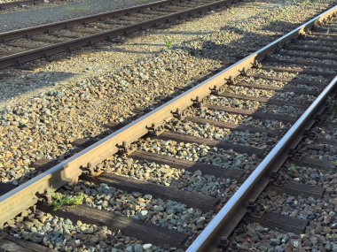 Çakıl taşlarında gün ışığında demiryolu rayları. Metal raylar ve ahşap yatakları gösteriyor..
