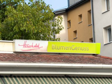 Althofen, Avusturya - 17 Eylül 2025: Parlak renklere ve çağdaş bina tasarımına sahip canlı bir kentsel alanda eski BlumenGenuss çiçek dükkanı tabelası