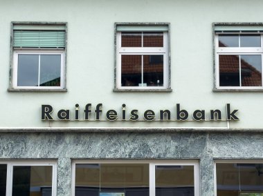 Althofen, Avusturya - 17 Eylül 2025: Raiffeisenbank 'ın dış cephesinde modern finansal hizmetler ve toplumsal ilişkileri simgeleyen büyük pencereler ve yeşil bir cephe yer almaktadır