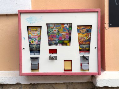 Althofen, Avusturya - 17 Eylül 2025: Vintage şeker otomatı renkli sakız ve oyuncaklar sergiliyor, yoldan geçenleri tatlı bir ziyafetin tadını çıkarmaya davet ediyor