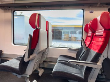 Althofen, Avusturya - 17 Eylül 2025: Kırmızı ve gri döşemeli çağdaş tren oturma düzeni, dış manzarayı ortaya çıkaran büyük pencere