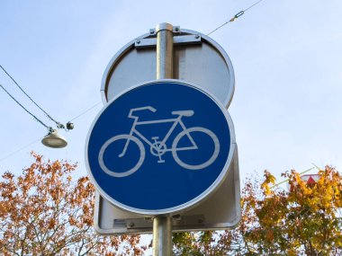 Sonbahar ağacı arkaplanına karşı mavi dairesel bisiklet yolu işareti.