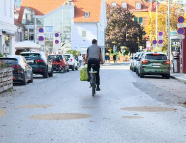 Graz, Avusturya - 11 Ekim 2025: Bisikletçi park halindeki araçlar ve büyüleyici binalarla çevrili kentsel caddede geziniyor, canlı bir bölgede çevre dostu gidip gelişleri vurguluyor