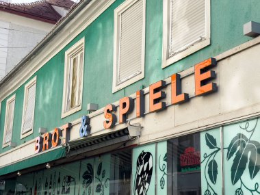Graz, Avusturya - 11 Ekim 2025: Brot & Spiele 'in yeşil duvarlı ve sanatsal pencere tasarımlı canlı bir şehir atmosferi yaratan canlı mağazası