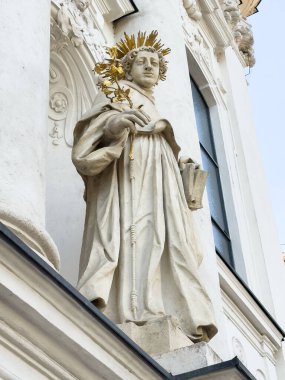 Graz, Avusturya - 11 Ekim 2025: Altın tacı olan aziz heykeli, elinde bir dal ve kitap, binanın dış kısmında güzelce detaylandırılmış.