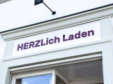Graz, Avusturya - 11 Ekim 2025: HerZlich Laden mağaza vitrininde yerel alışveriş ve toplumsal etkileşimler için ideal çağdaş bir işaret ve karşılama atmosferi yer almaktadır.