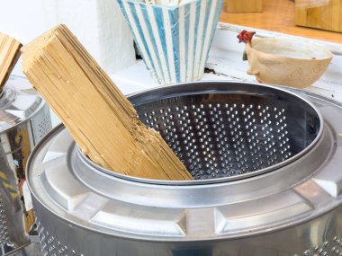 Graz, Avusturya - 11 Ekim 2025: Parlak bir çamaşır makinesi davulu içine yerleştirilmiş ahşap parça, kopya alanı olan yaratıcı bir ortamda dokuları ve tasarımı vurguluyor