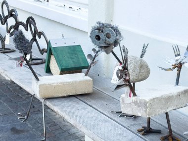 Graz, Avusturya - 11 Ekim 2025: Metal ve taştan yapılmış tuhaf hayvan heykelleri sanatsal bir açık hava ortamında ahşap bir bankta sergilenmektedir.