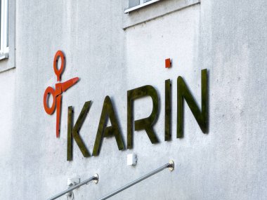 Graz, Avusturya - 11 Ekim 2025: KARIN kuaför salonu tabelası dokulu duvarda makas logosu, saç ve güzellik hizmetleri için bir karşılama alanı temsil ediyor