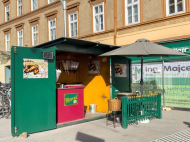 Graz, Avusturya - 11 Ekim 2025: Sokak yemekhanesi lezzetli sosisler ve dondurmalar sunuyor, yeşil tasarım ve açık havada oturma, canlı bir yemek deneyimi yaratıyor