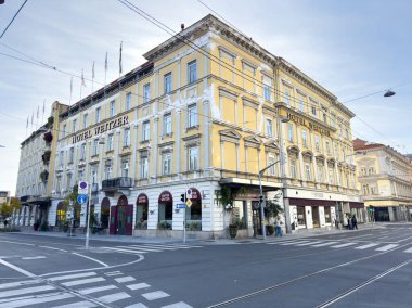 Graz, Avusturya - 11 Ekim 2025: Graz, Avusturya 'da tarihi bir yapı olan Weitzer Oteli, canlı bir şehir ortamında canlı sarı bir cephe ve zarif bir mimariye sahiptir.