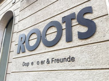 Graz, Avusturya - 11 Ekim 2025: Duvardaki kökler modern tasarım unsurlarını ön plana çıkarıyor, bir restoran veya kafe için davetkar bir atmosfer yaratıyor