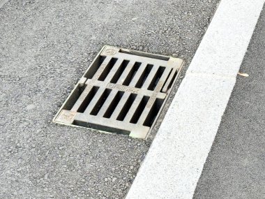 Graz, Avusturya - 11 Ekim 2025: Beton kaldırım kenarındaki asfalt yolda kurulmuş drenaj ızgarası, kentsel tasarım ve işlevselliği vurguluyor