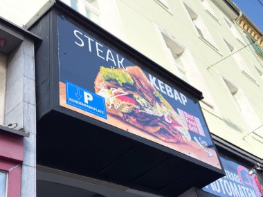 Graz, Avusturya - 11 Ekim 2025: Restoran tabelasında taze malzemeli biftek kebabı gösteriliyor, yoldan geçenleri lezzetli bir aşçılık deneyimi yaşamaya davet ediliyor