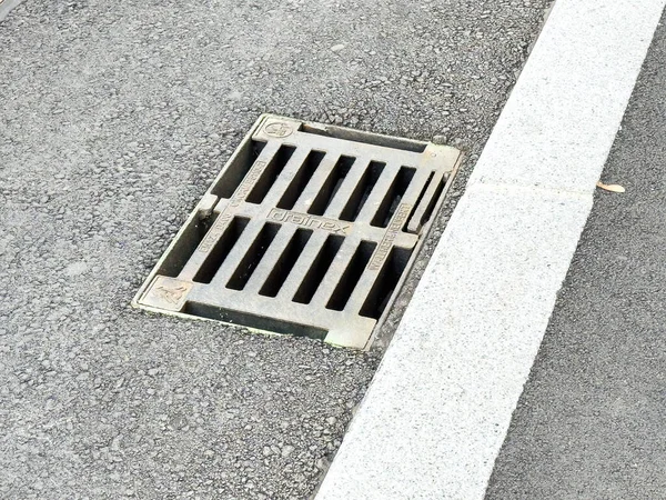 Graz, Avusturya - 11 Ekim 2025: Beton kaldırım kenarındaki asfalt yolda kurulmuş drenaj ızgarası, kentsel tasarım ve işlevselliği vurguluyor