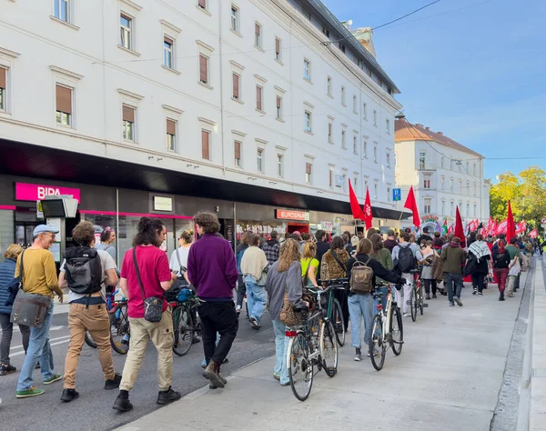 Graz, Avusturya - 11 Ekim 2025: Şehir caddesinde renkli bayraklar ve binalarla çevrili bir protestoya katılan çeşitli bisikletçi grubu