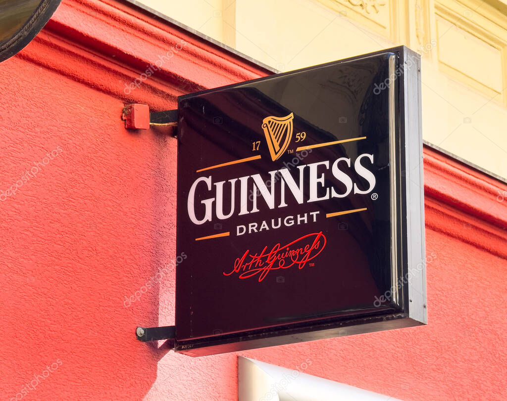 Graz, Austria - October 11, 2025: Guinness Draught sign is featured on a bright red wall, highlighting the famous logo and inviting ambiance of the pub