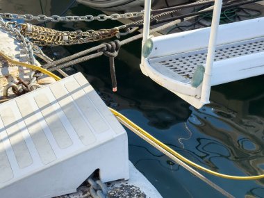 Limandaki beyaz rıhtım rampası ve halatlar suya yansıyor..