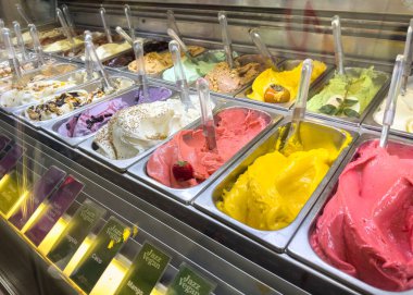 Trieste, İtalya - 14 Ekim 2025: Çağdaş bir dondurmacıda çeşitli aromalı dondurma sergisi, canlı renkler ve dokular