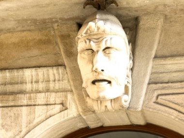 Trieste, İtalya - 14 Ekim 2025: Tarihi taş surat heykeli, sanatsal ayrıntıları ve kültürel önemi vurgulayarak bir kapı aralığının üzerinde belirgin bir şekilde sergilenmektedir