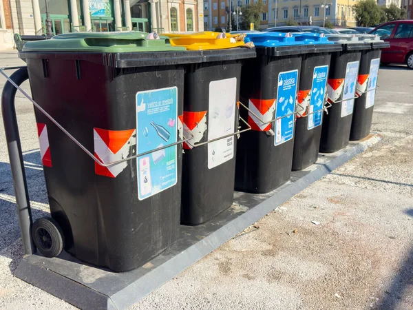 Trieste, İtalya - 14 Ekim 2025: Sokağa dizilmiş renkli geri dönüşüm konteynırları, kentsel alanlarda atık ayrımını ve çevre dostu uygulamaları teşvik