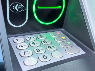 Yeşil temassız ödeme ışığı olan ATM tuş takımına yakın çekim.
