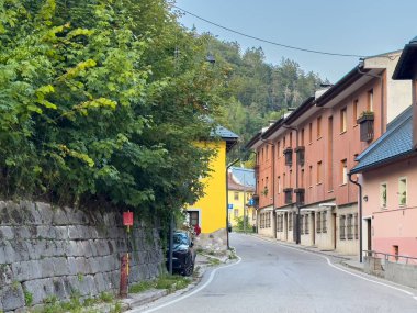 Tarvisio, İtalya - 19 Ağustos 2025: Tuhaf bir köyde dar bir sokakta renkli binalar ve canlı yeşillikler var, barışçıl ve davetkar bir ortam yaratıyorlar.