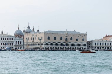 Venedik, İtalya - 23 Haziran 2025: Venedik, İtalya 'daki Doge Sarayı, zengin tarih ve mimariyi yansıtan gondollarla görkemli bir şekilde suyun kenarında duruyor.