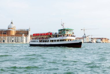 Venedik, İtalya - 23 Haziran 2025: Feribot Altiero tarihi binalar ve arka planda canlı bir atmosferle Venedik sularında geziniyor.