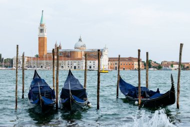 Venedik, İtalya - 23 Haziran 2025: Gondollar Venedik 'in sularına demirlemiş, çarpıcı San Giorgio Maggiore kilisesini ve huzurlu çevresini vurguluyorlar.