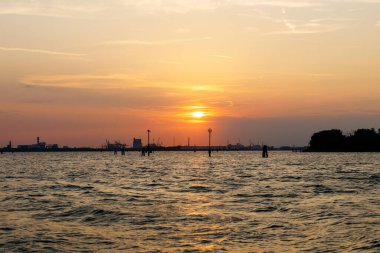 Venedik, İtalya - 23 Haziran 2025: Yapıların siluetleriyle sakin günbatımı sahnesi, alacakaranlığın barışçıl atmosferini ve doğal güzelliğini gözler önüne seriyor