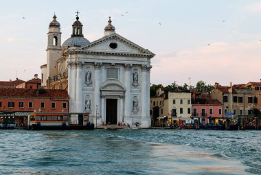 Venedik, İtalya - 23 Haziran 2025: Venedik, İtalya 'daki güzel Santa Maria della Salute Kilisesi, Büyük Kanal' daki renkli binalar ve teknelerle çevrili.