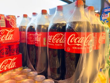 Villach, Avusturya - 23 Ekim 2025: Coca-Cola şişeleri plastiğe sarılı bir markette belirgin bir şekilde sergileniyor, ikonik marka ve canlandırıcı içecek seçimi vurgulanıyor