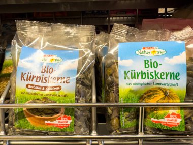 Villach, Avusturya - 23 Ekim 2025: Açık pakette organik balkabağı tohumları bir süpermarket rafında düzenlenerek, sağlıklı alışverişçiler için besleyici aperatif seçenekleri vurgulanıyor