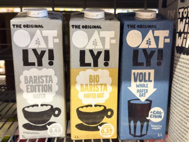 Villach, Avusturya - 23 Ekim 2025: Yulaf ezmeli süt kutuları süpermarket raflarında farklı aromalar ve vegan tercihleri için canlı ambalajlar sunuluyor.